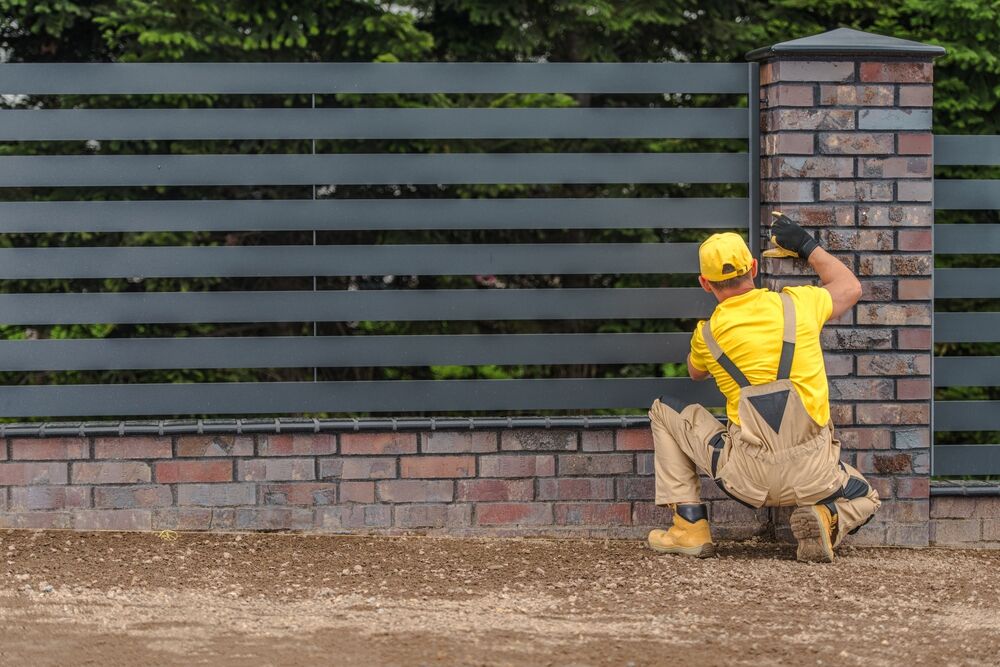 Fence contractor installing an entry fence and gate - Bella Vista Contractors